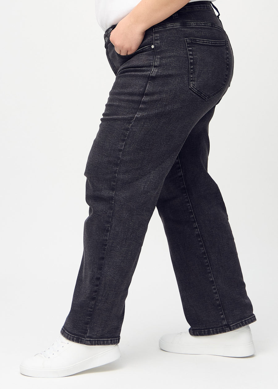Dark grey denim loose jeans seen from the side on a plus-size model.