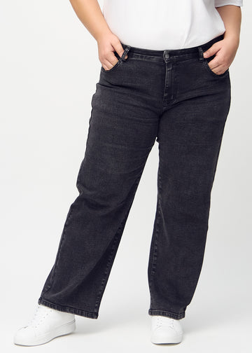 Dark grey denim loose jeans, model name Shadows, which has a loose fit with plenty of width in the legs on a plus-size model, seen from the front.