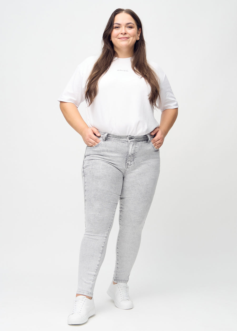 Full image of a plus-size model in light grey denim skinny jeans.