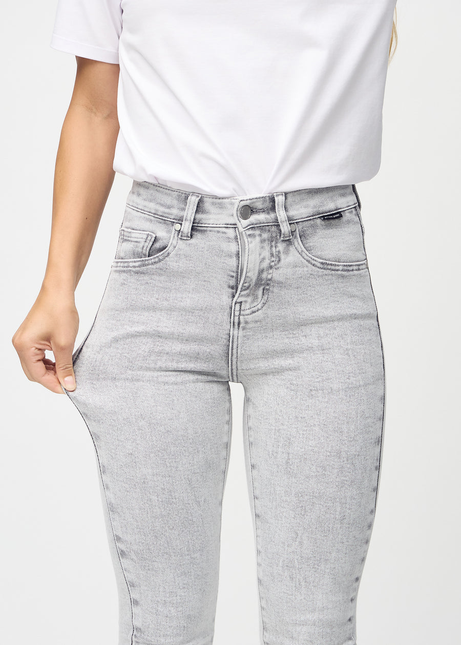 The model stretches the jeans at the thigh to show the stretch.