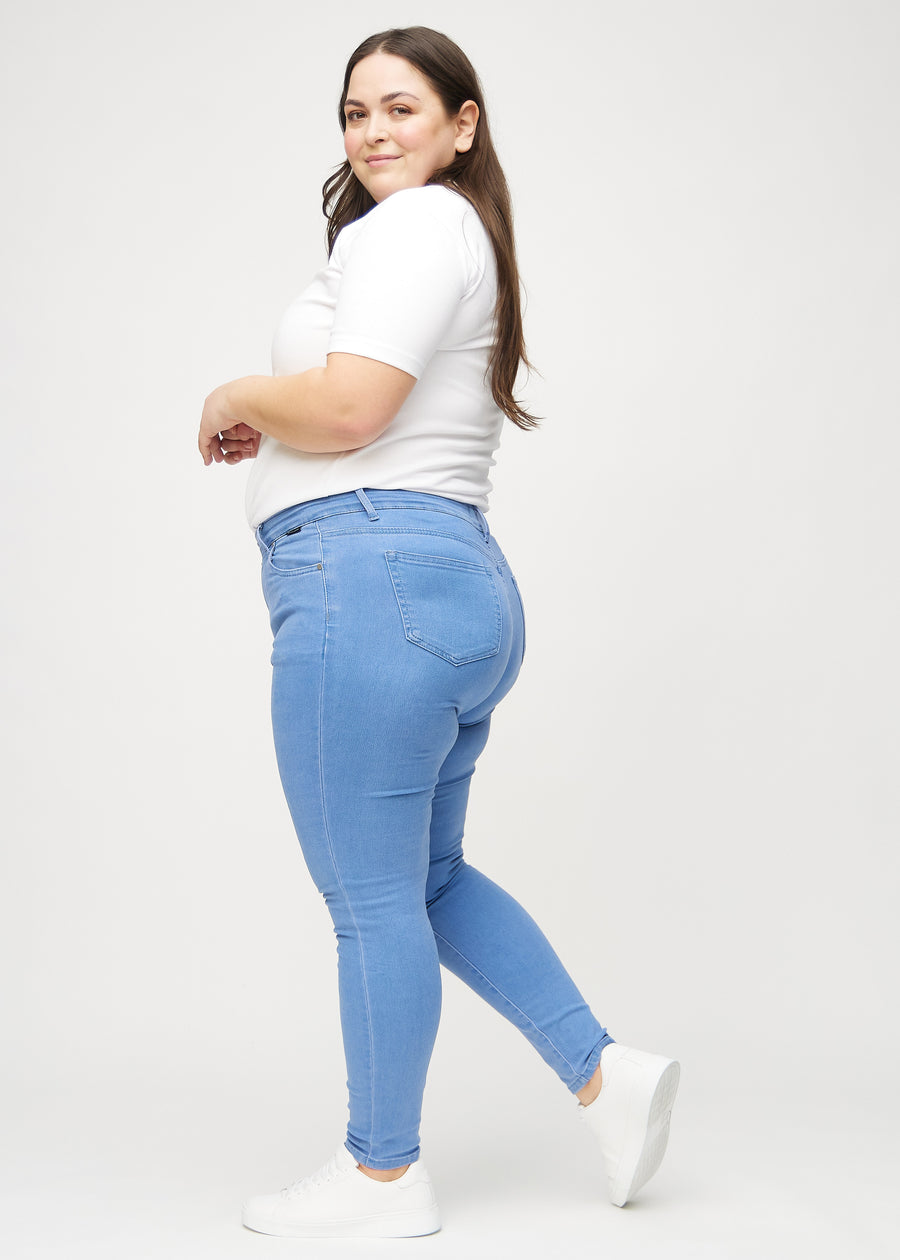 Skinny jeans for women in blue, color Geraniums. Side view on a plus-size model.