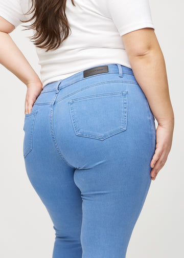 Skinny jeans for women in blue, color Geraniums. Close-up back view on a plus-size model, showing the details.