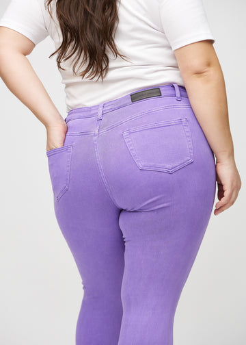 Skinny jeans for women in purple, color Lavenders. Close-up back view on a plus-size model, showing details.