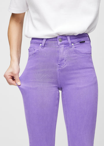 Skinny jeans for women in purple, color Lavenders. A model stretches the jeans at the thigh to show the fabric&