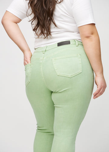 Skinny jeans for women in light green, color Mints. Close-up back view on a plus-size model, showing details.