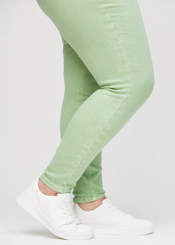 Skinny jeans for women in light green, color Mints. Close-up of the snug-fitting leg openings at the ankles on a plus-size model.