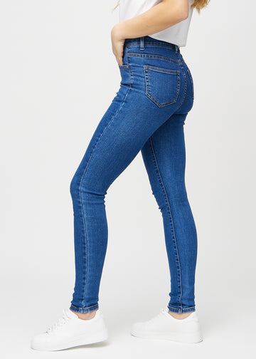Skinny jeans for women in dark blue, color Oceans. Side view on a model.