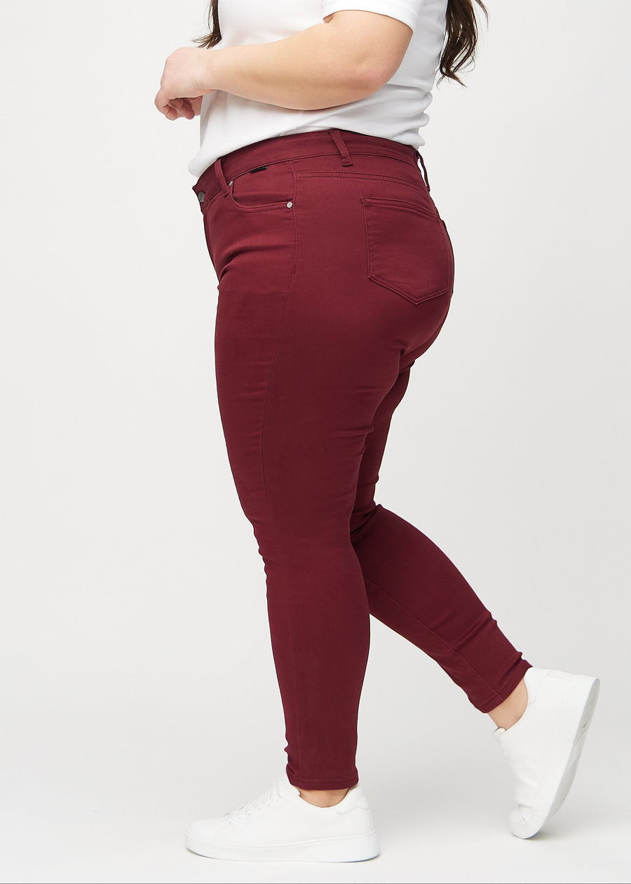 Skinny jeans for women in dark red, color Santas. Side view on a plus-size model.