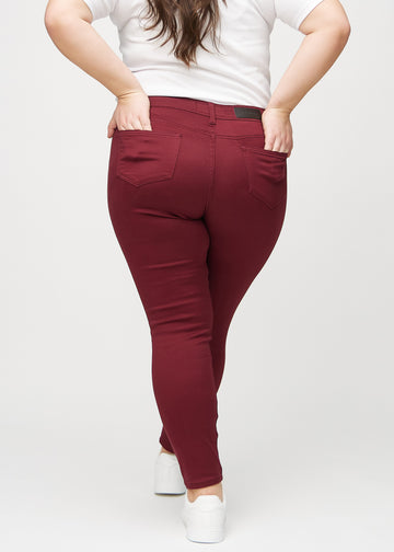 Skinny jeans for women in dark red, color Santas. Back view on a plus-size model, showing the full fit.