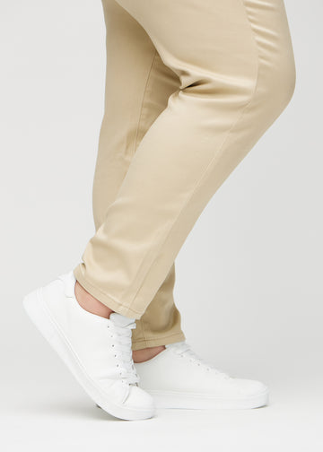 Slim jeans for women in beige, color Gazelles. Close-up at the ankles on a plus-size model, showing the fit at the leg openings.