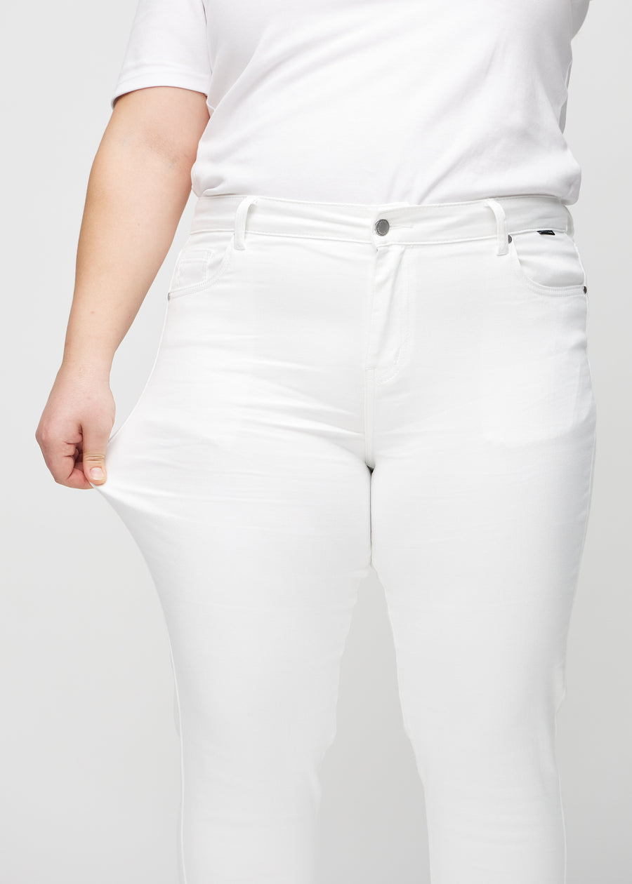 Slim jeans for women in white, color Marguerites. A plus-size model stretches the jeans at the thigh to show the fabric&