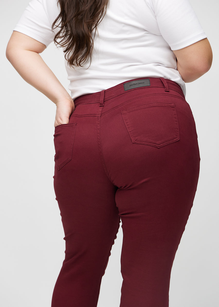 Slim jeans for women in dark red, color Santas. Close-up back view on a plus-size model, showing the details.