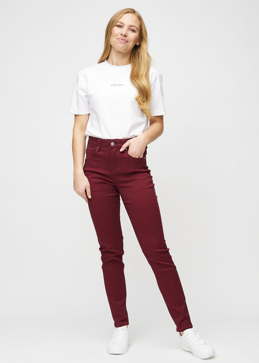 Slim jeans for women in dark red, color Santas. Full-length view of a model wearing the jeans.