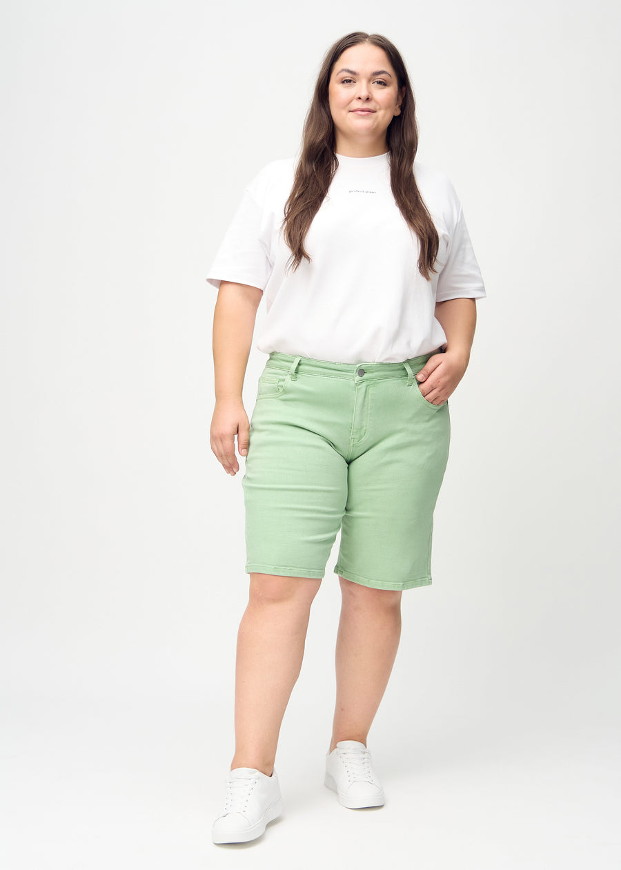 Full image of a plus-size model in light green regular middle shorts.
