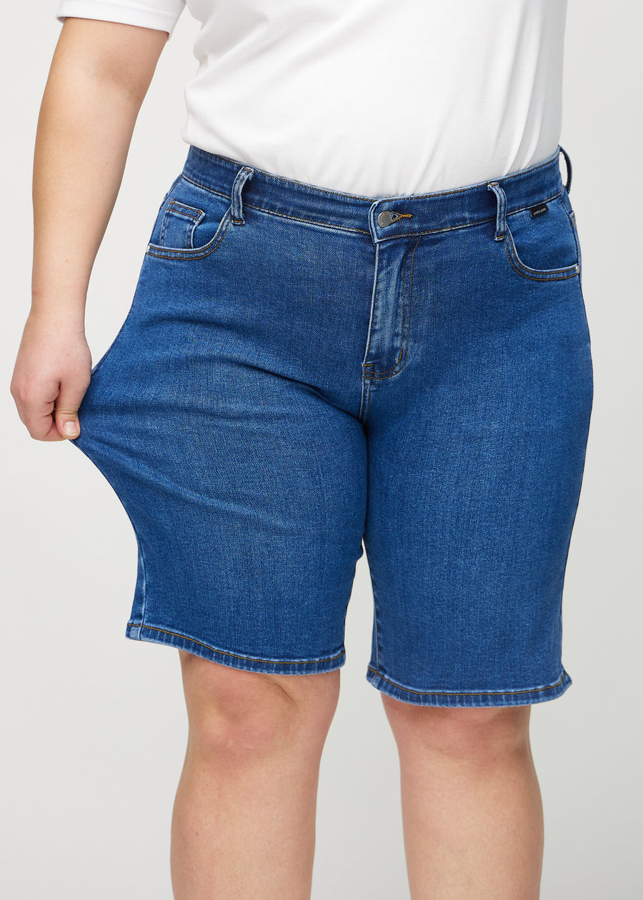 The plus-size model stretches the shorts at the thigh to show the stretch.