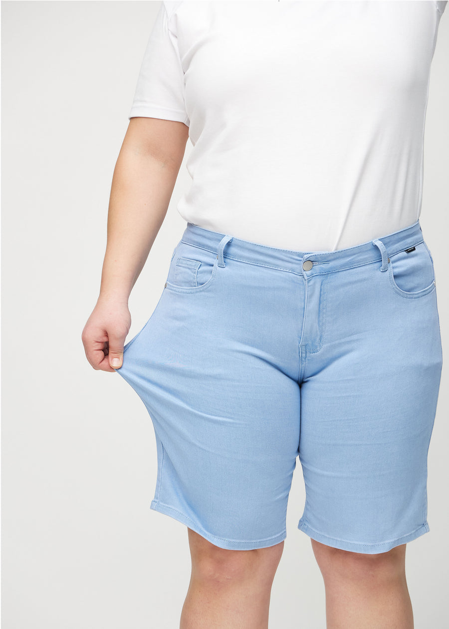The plus-size model stretches the shorts at the thigh to show the stretch.