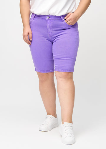 Purple skinny middle shorts, style name Lavenders, which fit closely around the thigh and end just above the knee on a plus-size model, seen from the front.