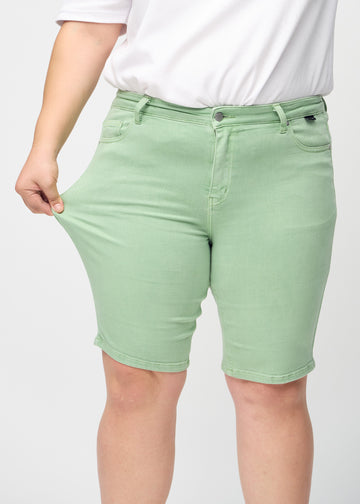 The plus-size model stretches the shorts at the thigh to show the stretch.