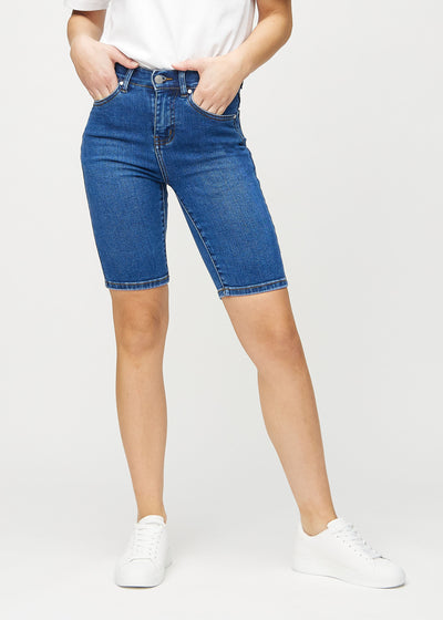 Dark denim skinny middle shorts, model name Oceans, which fit closely around the thigh and end just above the knee, seen from the front.