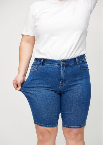 The plus-size model stretches the shorts at the thigh to show the stretch.