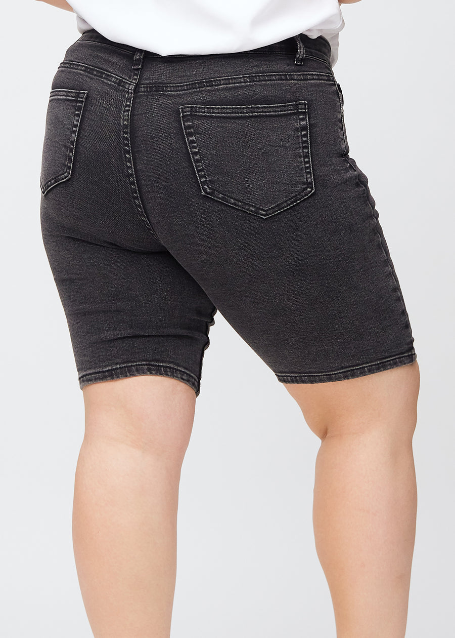 Dark grey denim skinny middle shorts seen from the back in close-up on a plus-size model to show details.