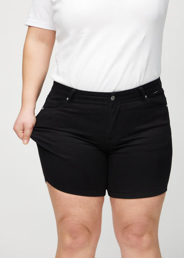The plus-size model stretches the shorts at the thigh to show the stretch.