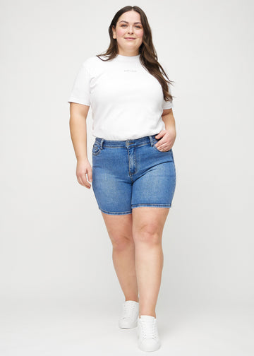 Full image of a plus-size model in denim skinny short shorts.