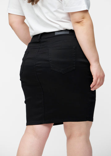 Sort, tætsiddende og knælang jeansnederdel set bagfra tæt på på plus-size model for at vise detaljer.