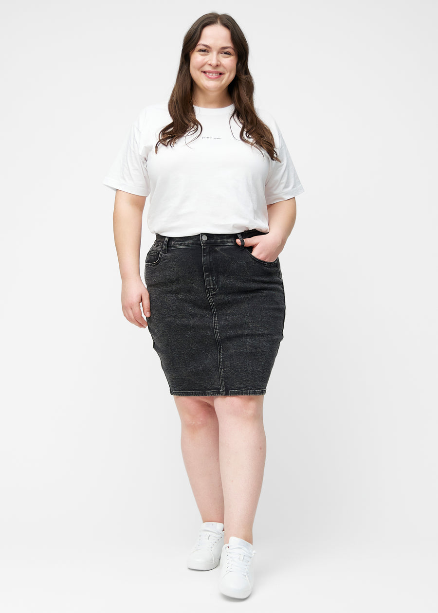 Fuldt billede af plus-size model i mørkegrå, tætsiddende og knælang denimnederdel.