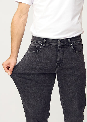The model stretches the jeans at the thigh to show the stretch.