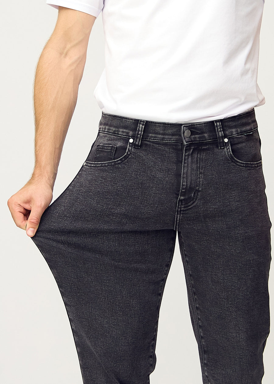 The model stretches the jeans at the thigh to show the stretch.
