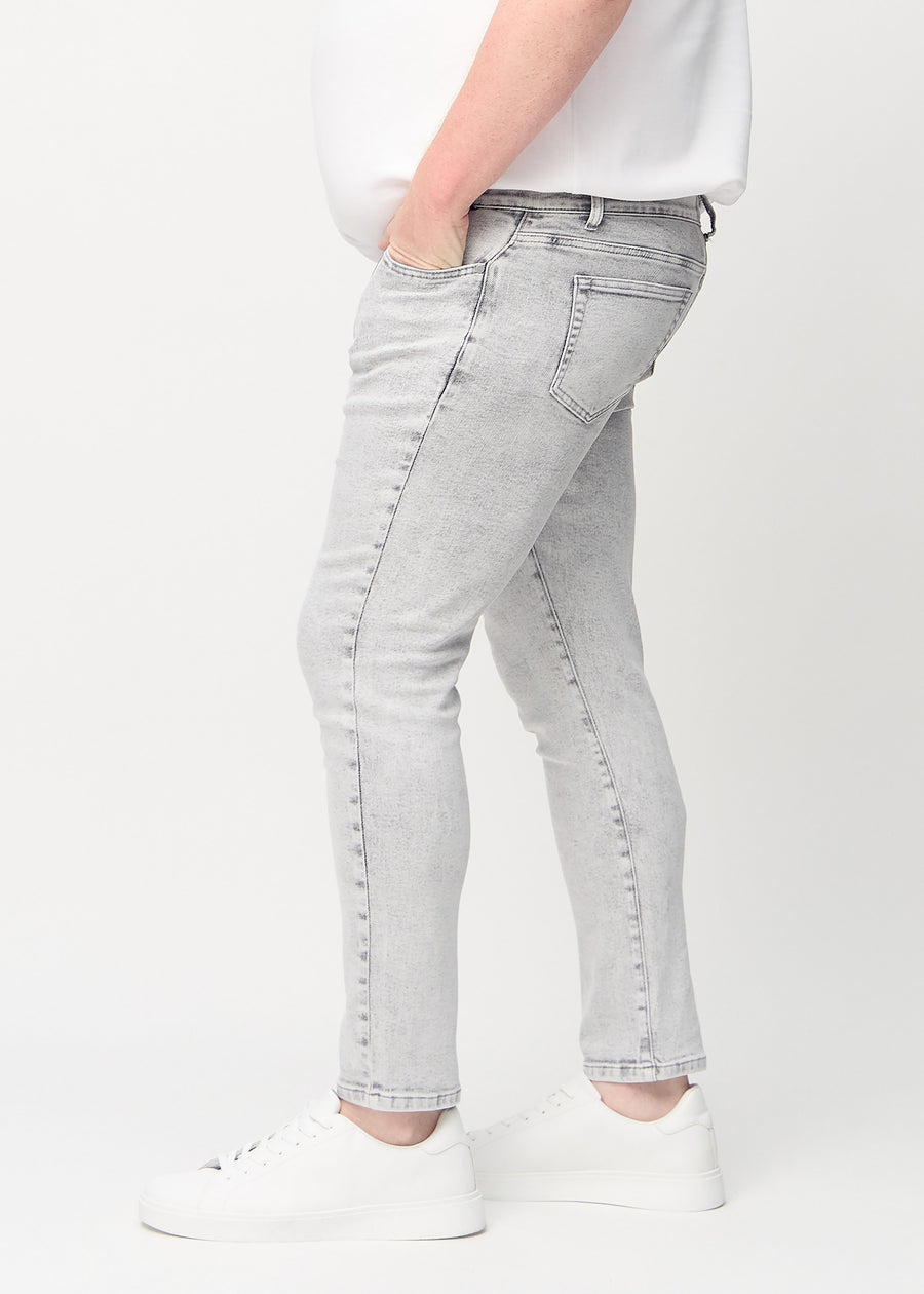 Light grey denim slim jeans viewed from the side on a plus-size model.