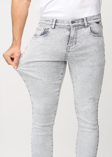 Model stretches the jeans at the thigh to show the fabric&