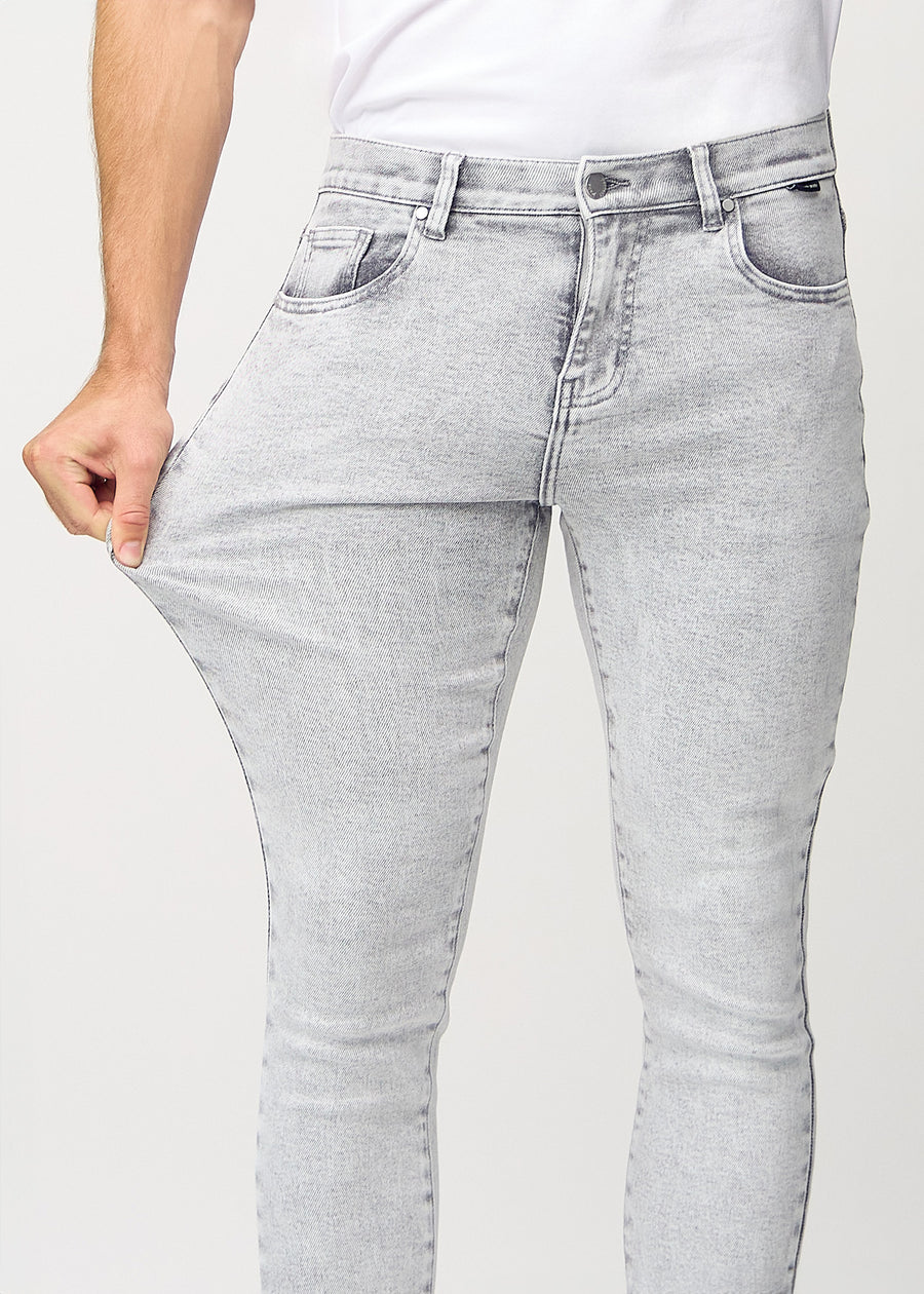 Model stretches the jeans at the thigh to show the fabric&
