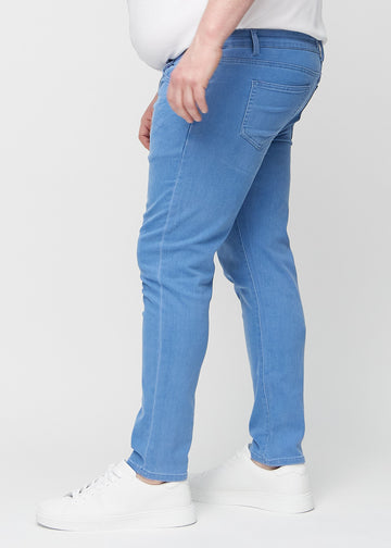 Blue slim jeans viewed from the side on a plus-size model.