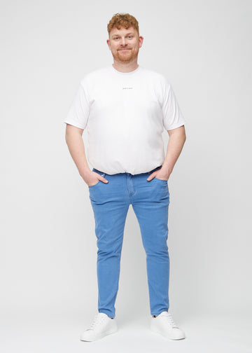 Full-length view of a plus-size model in blue slim jeans.