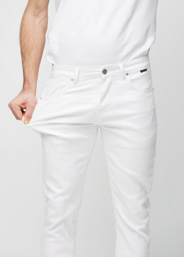Model stretches the jeans at the thigh to show the fabric&