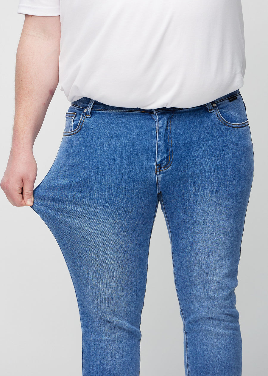 Plus-size model stretches the jeans at the thigh to show the fabric&