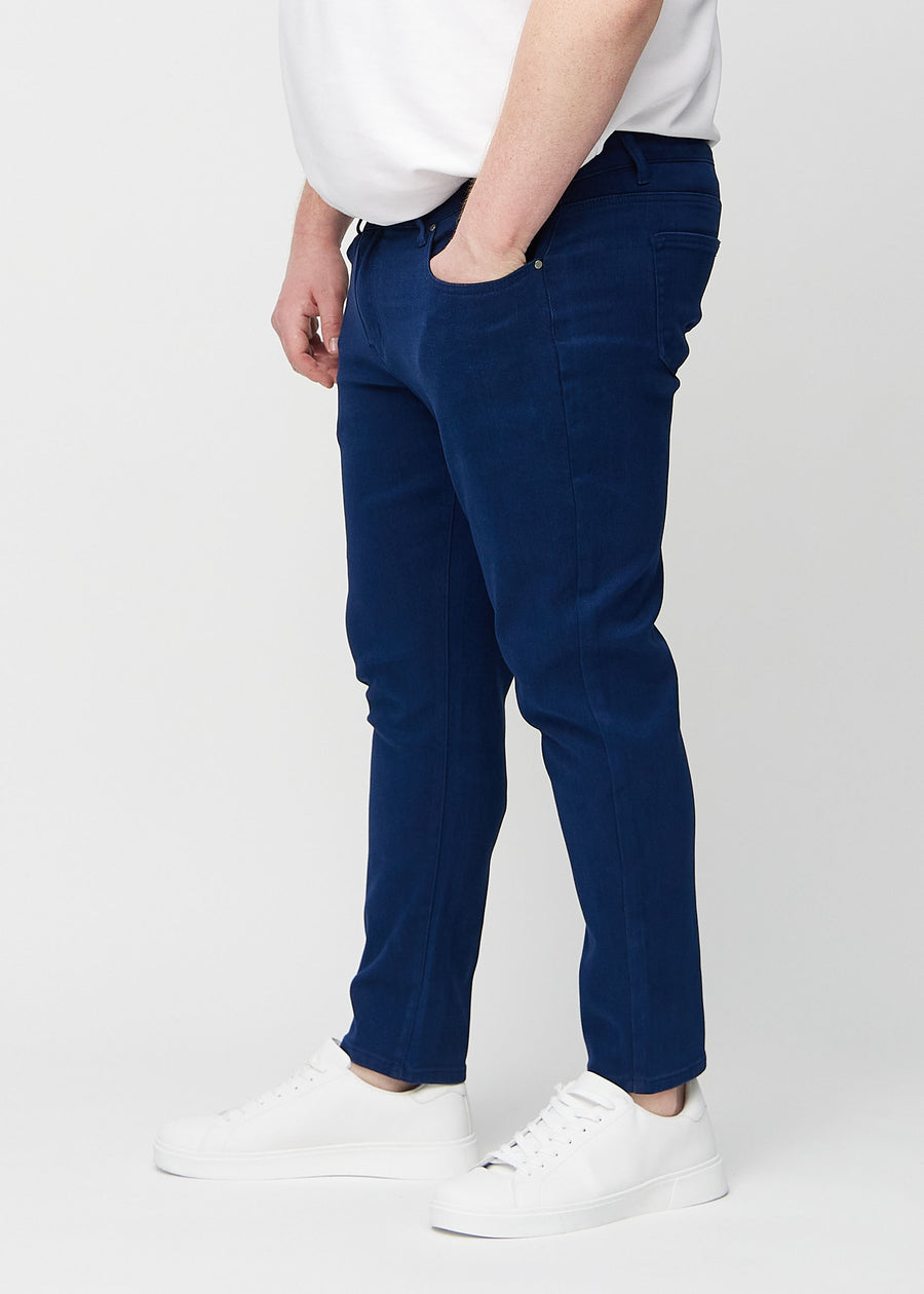 Dark blue slim jeans viewed from the side on a plus-size model.