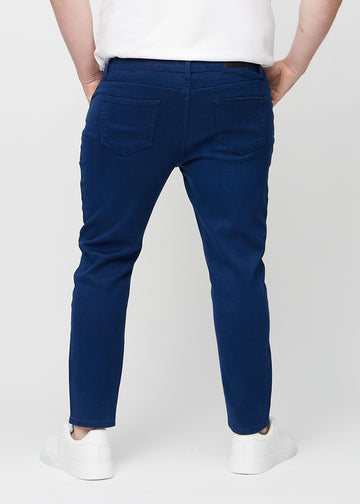Dark blue slim jeans viewed from the back on a plus-size model to show the full product.