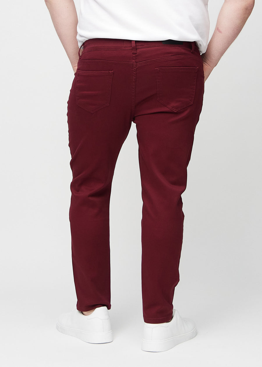 Dark red slim jeans viewed from the back on a plus-size model to show the full product.