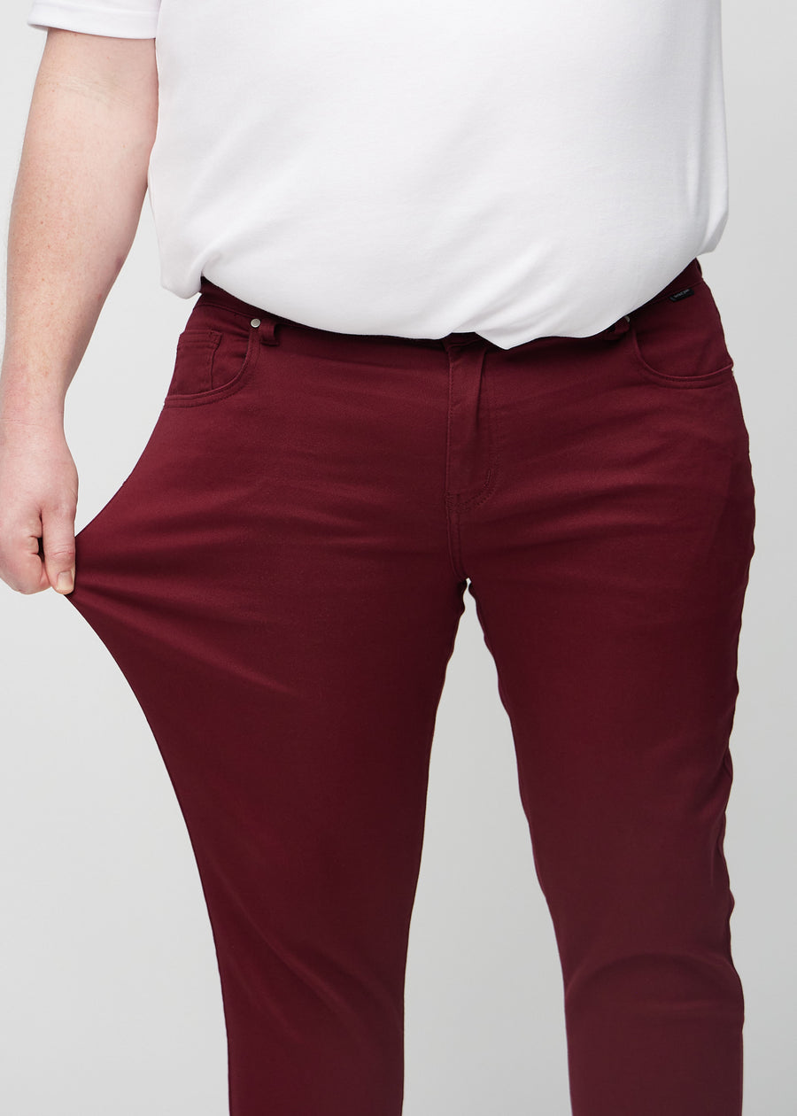 Plus-size model stretches the jeans at the thigh to show the fabric&