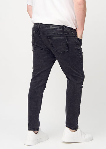 Dark grey denim slim jeans viewed from the back on a plus-size model to show the full product.