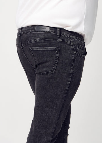 Close-up back view of dark grey denim slim jeans on a plus-size model showing details.