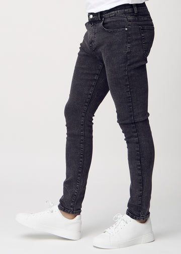 Dark grey denim slim jeans viewed from the side on a model.
