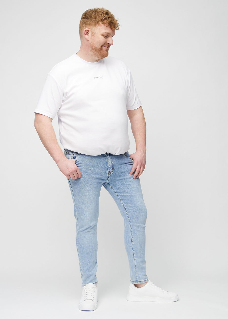 Full-length view of a plus-size model in light blue denim slim jeans.