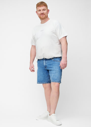 Plus-size model viser blå denim shorts til mænd i farven Rivers med regular pasform i bevægelse.