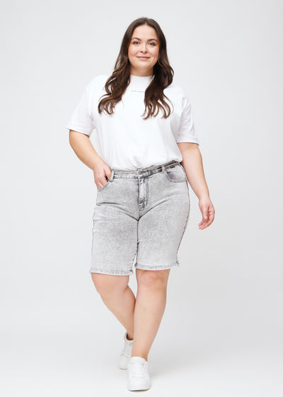 Plus-size model går ind i billedet, strækker i sine shorts, viser dem frem ved at dreje rundt, og forlader derefter billedet.