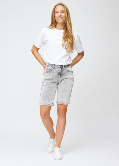 Model går ind i billedet, strækker i sine shorts, viser dem frem ved at dreje rundt, og forlader derefter billedet.