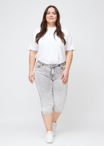Plus-size model går ind i billedet, strækker i sine capris, viser dem frem ved at dreje rundt, og forlader derefter billedet.
